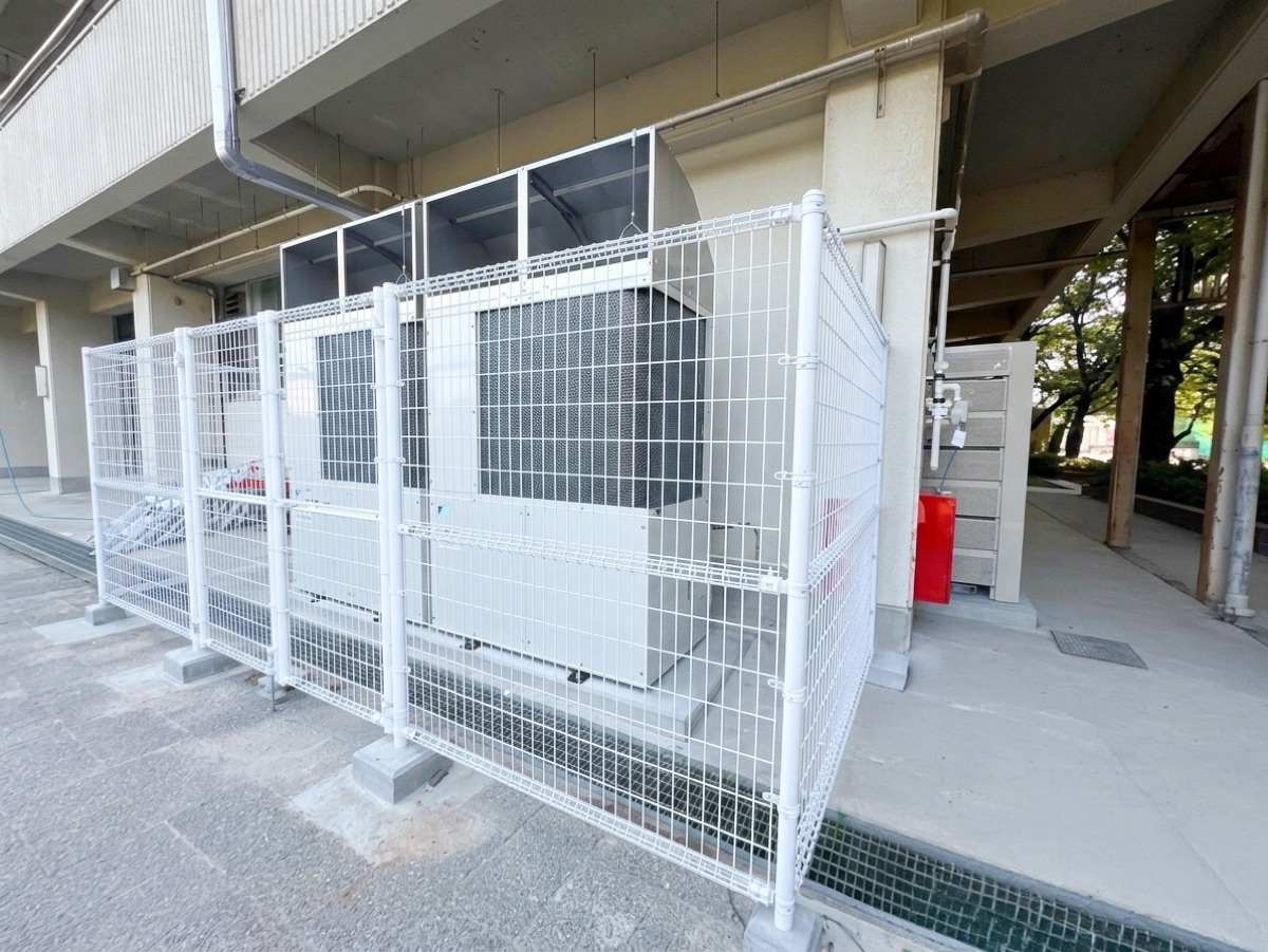 校舎下のスペースにフェンスで囲って設置した室外機